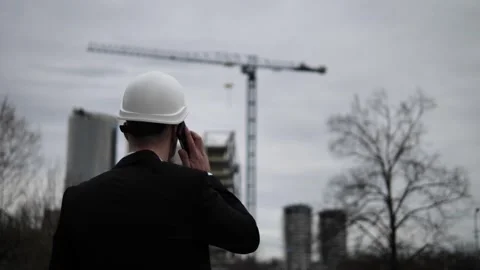 Architect phone pressed to ear directs construction site activity ensures Stock Footage 271326665