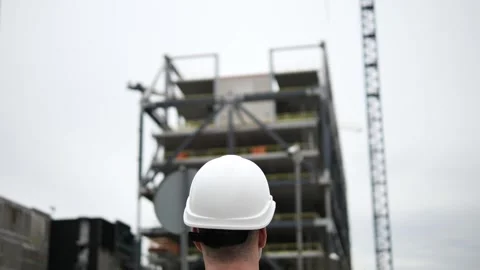 Architect phone pressed to ear directs construction site activity ensures Stockbeeldmateriaal 275286612