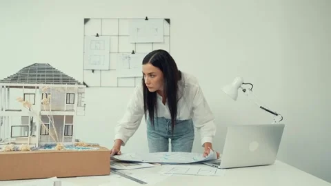 Architect puts blueprint on the table and compare with house model. Immaculate. Stock Footage 274226912