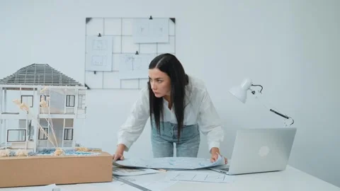 Architect puts blueprint on the table and compare with house model. Immaculate. Stock Footage 278245906