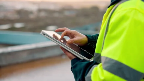 Architect, scroll and hands with tablet at building site, search and safety Stock Footage 336190005