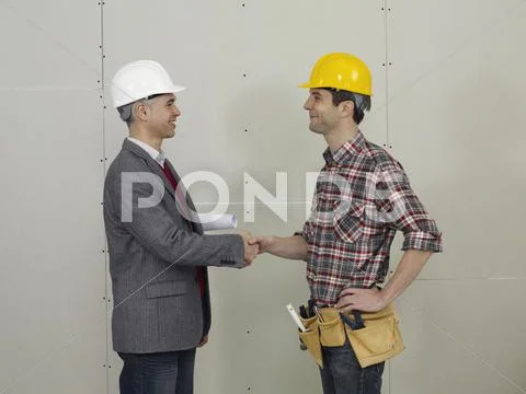 An architect shaking hands with a construction worker Stock Photos