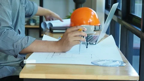 Architect is sitting in front of computer and holding divider Stock Footage 92593772