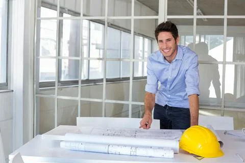 Architect smiles at camera while coworkers stand in background Stock Photos