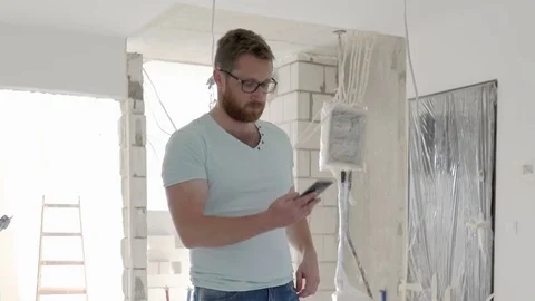 Architect standing in the new flat and talking on cellphone, steadycam shot Stock Footage 76501974