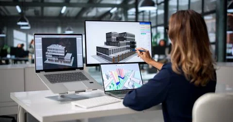 Architect Studies 3D BIM Model On Laptop, Planning City Building Project. Stock Photos