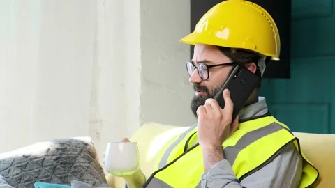 Architect talking on the phone and drinking a cup of tea, relaxing on sofa. Stock Footage 152647652