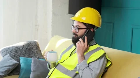 Architect talking on the phone and drinking a cup of tea, relaxing on sofa. Stock Footage 152980224