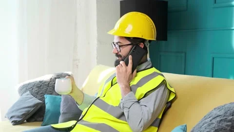 Architect talking on the phone and drinking a cup of tea, relaxing on sofa. Stock Footage 153104155