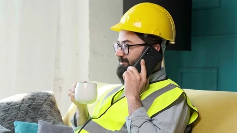 Architect talking on the phone and drinking a cup of tea, relaxing on sofa. Stock Footage 155404714