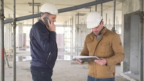 Architect talking by smartphone while second one browsing building project. Vidéo 72359141