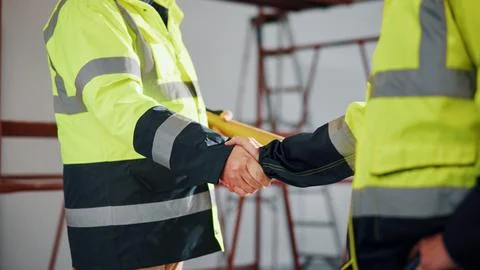 Architect, team and shaking hands with blueprint in building, agreement and Stock Photos