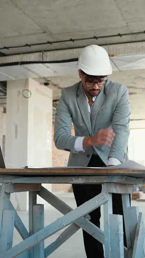 Architect using laptop and reviewing blueprints on construction site Stock Footage 312845467