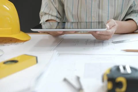 Architect using tablet. engineer working on house blueprint of real estate pr Stock Photos
