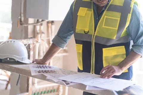 Architect in vest checking project papers and documents stands in room Stock Photos