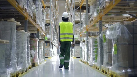 Architect walking through logistics shelves of factory using tablet. female in Видео 124451747