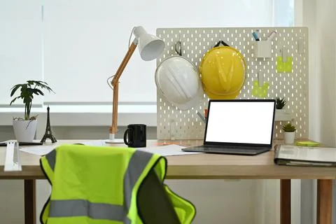 Architect working desk with laptop computer, hardhat, reflective jacket and Stock Photos