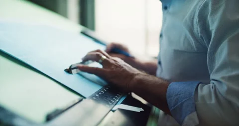 Architect working at a drafting table drawing architectural blueprints in a mode Stock Footage 199456322