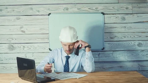 An architect working on drawings of new projects and talking on the phone . A 스톡 동영상 104202412