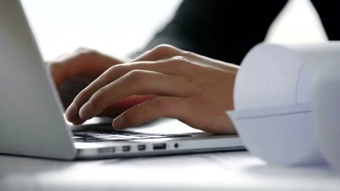 Architect Working on Laptop with Design Drawings in Office Stock Footage 302228130
