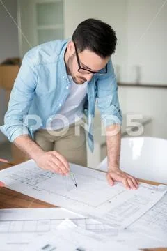 Architect working on plans at home office table Stock Photos