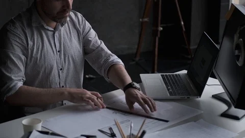 Architect works with drawings while sitting in a modern loft-style office. Stock Footage 107329427