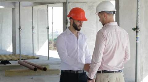 Architector and builder shake hands at the building under construction Stock Footage