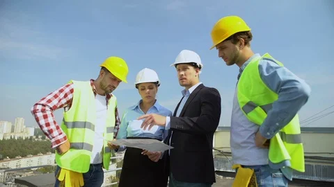 Architects discussing building plan with construction workers standing roof Stock-Footage 117218781