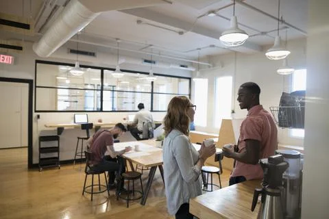 Architects drinking coffee and talking in open plan office Stock Photos