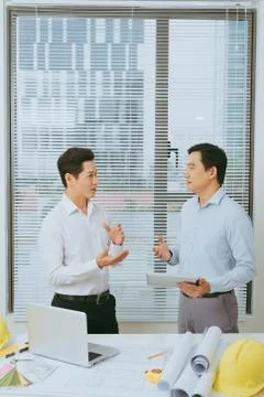 Architects engineer discussing at the table with blueprint of architectural p Stock Photos