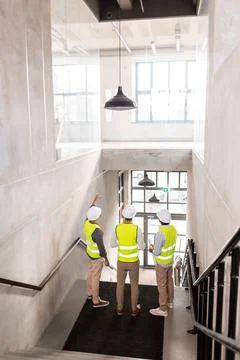 Architects in helmets with blueprints at office 스톡 사진