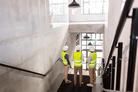Architects in helmets with blueprints at office 스톡 사진
