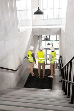Architects in helmets with blueprints at office Stock Photos