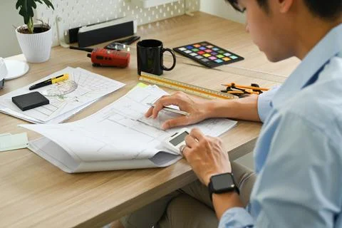 Architects man using mobile phone, working on design of a construction plan at Foto stock