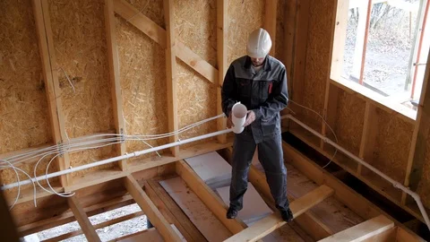 Architects or builder check plans in a half built timber frame house. Builder on Stock Footage 96898031