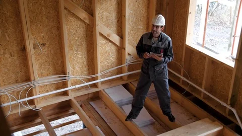 Architects or builder check plans in a half built timber frame house. Smiling Stock Footage 96901192