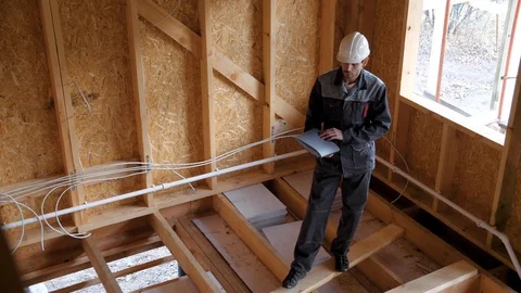 Architects or builder check plans in a half built timber frame house. Builder on Stock-Footage 96906279