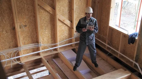 Architects or builder check plans in a half built timber frame house. Builder on Stock-Footage 103310942