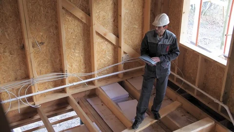 Architects or builder check plans in a half built timber frame house. Builder on Video stock 103311450