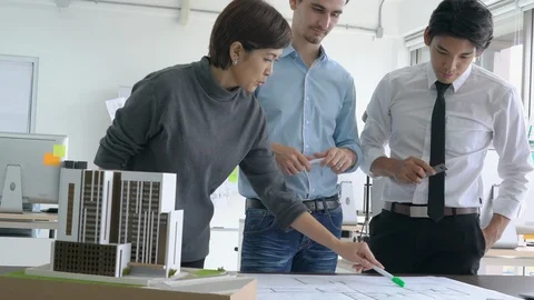 Architects team are working on paper blueprint and building model. Stock Footage 106670473