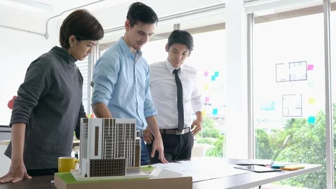 Architects team are working on paper blueprint and building model. Video stock 108669927