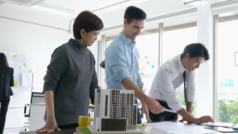 Architects team are working on paper blueprint and building model. Video stock 108671364