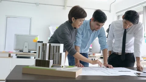 Architects team are working on paper blueprint and building model. Stock Footage 108674046
