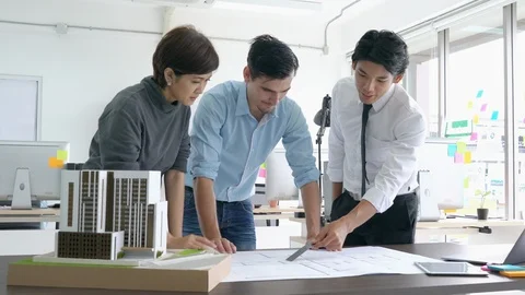 Architects team are working on paper blueprint and building model. Video stock 108676390