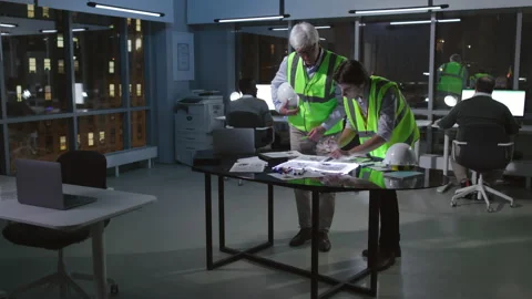 Architects in uniform work in loft office in midtown with night city view Stock Footage 176197152