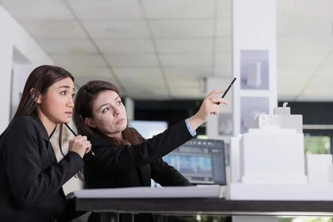 Architects working with project draft, discussing building 3d model Fotos de archivo