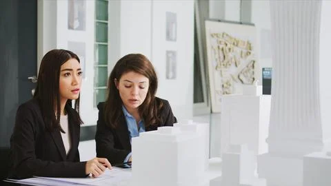Architectural agency workers taking notes on blueprints Stock Photos