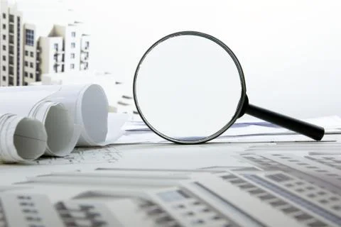 Architectural blueprints, blueprint rolls and magnifying glass on white Stock Photos