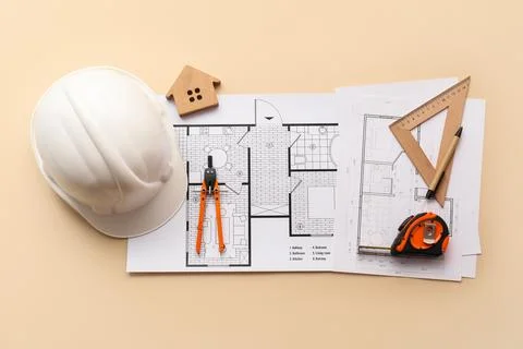 Architectural blueprints with construction tools and safety helmet on beige b Stock Photos