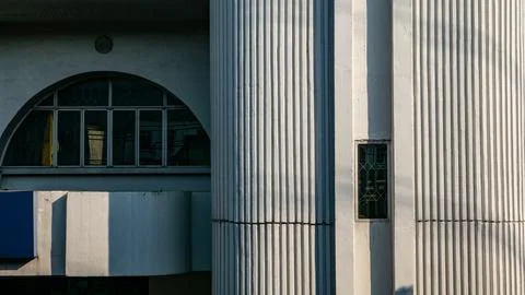 Architectural contrast between an arched window building and a white ribbed.. 스톡 사진